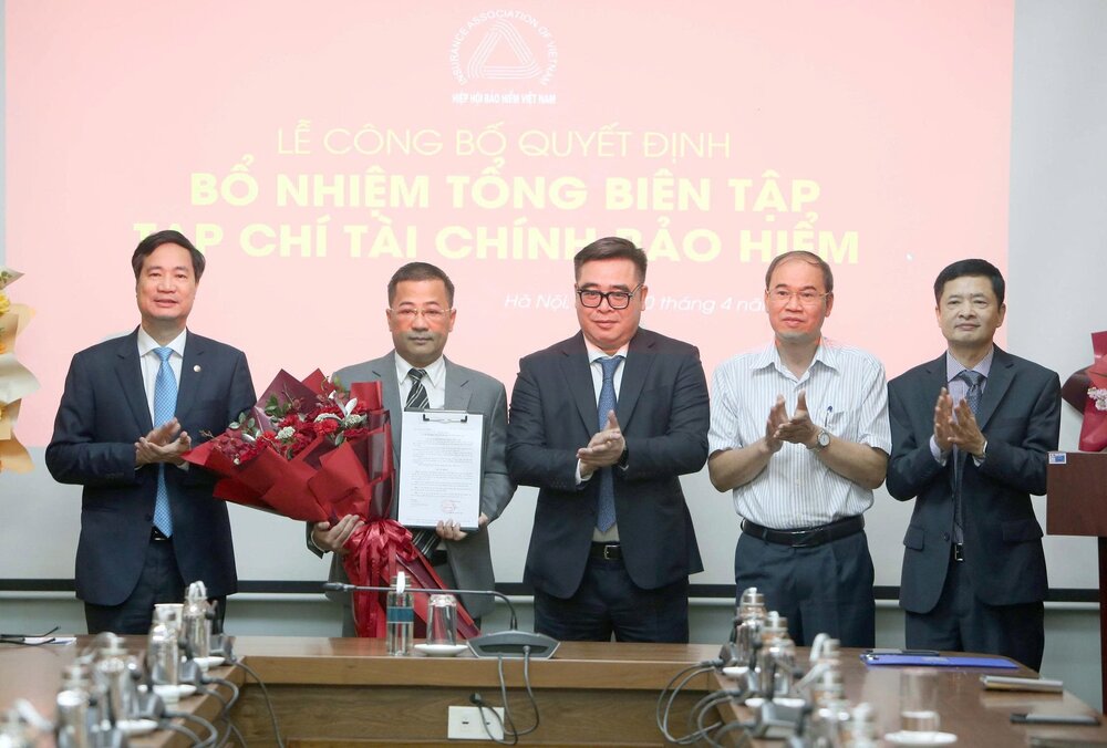 Cục Trưởng Cục Quản lý, Giám sát Bảo hiểm Ngô Việt Trung, Phó Cục Trưởng Cục Quản lý, Giám sát Bảo hiểm Phạm Văn Đức, Chủ tịch Hiệp hội Bảo hiểm Việt Nam Nguyễn Xuân Việt và Tổng thư ký Hiệp hội Bảo hiểm Việt Nam Phạm Ngọc Sơn, tặng hoa chúc mừng nhà báo Nguyễn Phong Cầm. Ảnh: Tuấn Minh